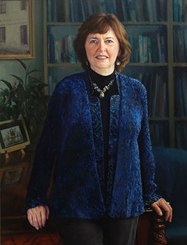 commissioned portrait of woman in blue standing in an academic office space.