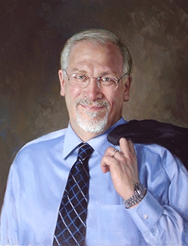 commissioned portrait of man smiling in suit and dress shirt, with blazer thrown over the shoulder.