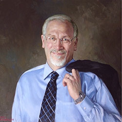 commissioned portrait of man smiling in suit and dress shirt, with blazer thrown over the shoulder.