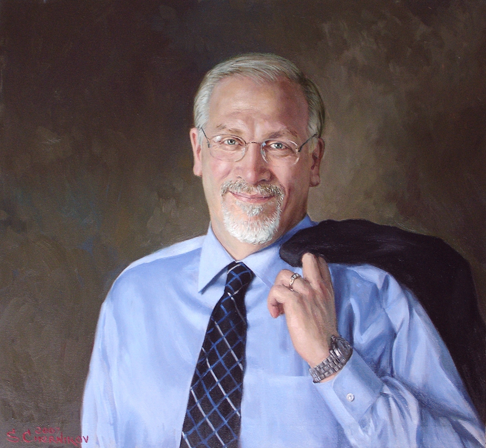 commissioned portrait of man smiling in suit and dress shirt, with blazer thrown over the shoulder.