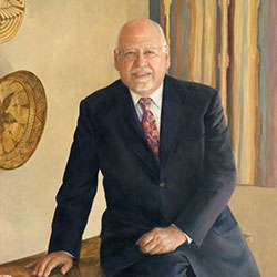 commissioned portrait of older man in suit and tie leaning against desk. 