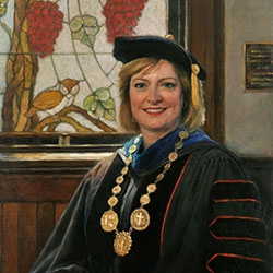 commissioned portrait of woman in academic robes and cap, holding a book.